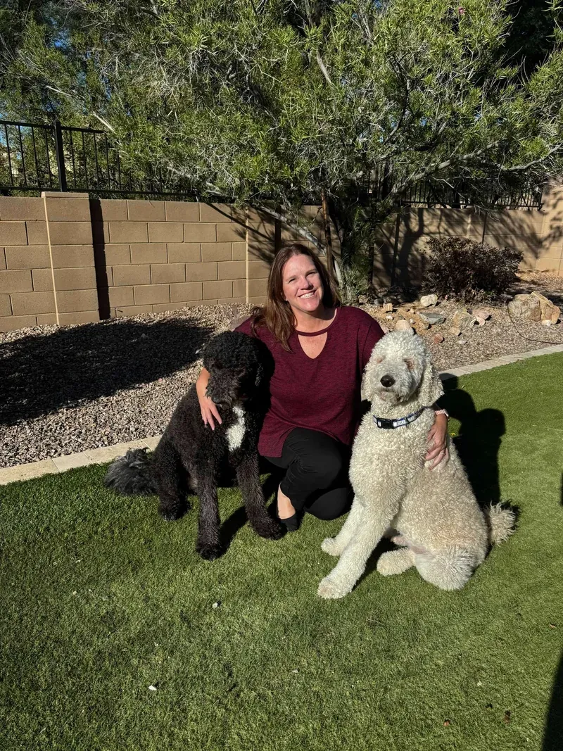 Carrie Igondjo in her backyard with her two shepadoodles, one black and one cream